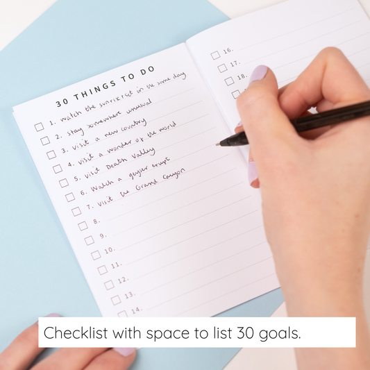 Hand writing on a checklist with space to list 30 goals on a light blue background